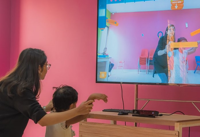 A child and an adult playing a WonderTree augmented-reality game on a screen