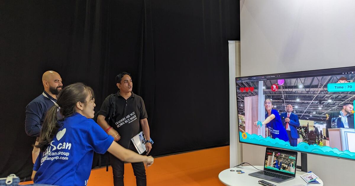 Visitors playing a WonderTree motion game on a large screen at an expo stand